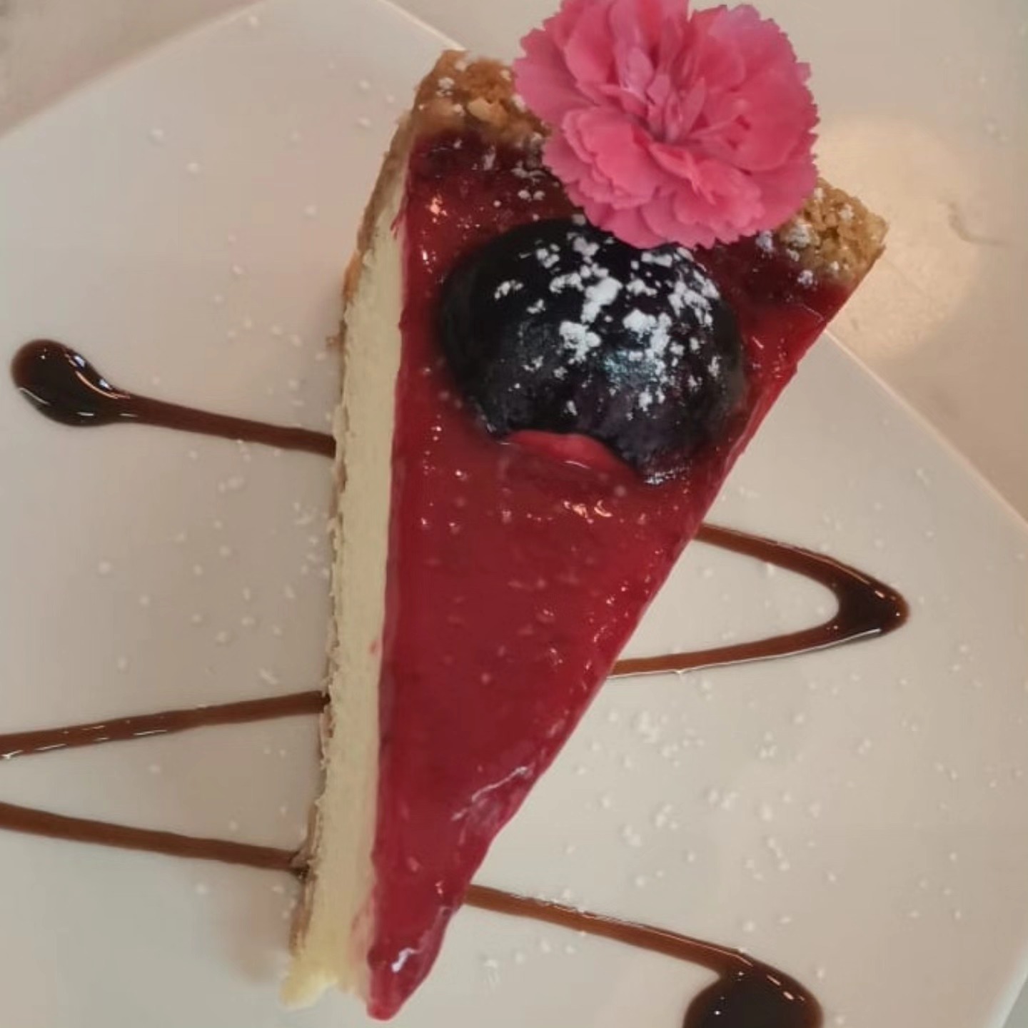 Caramel cheesecake slice with berries and edible flower