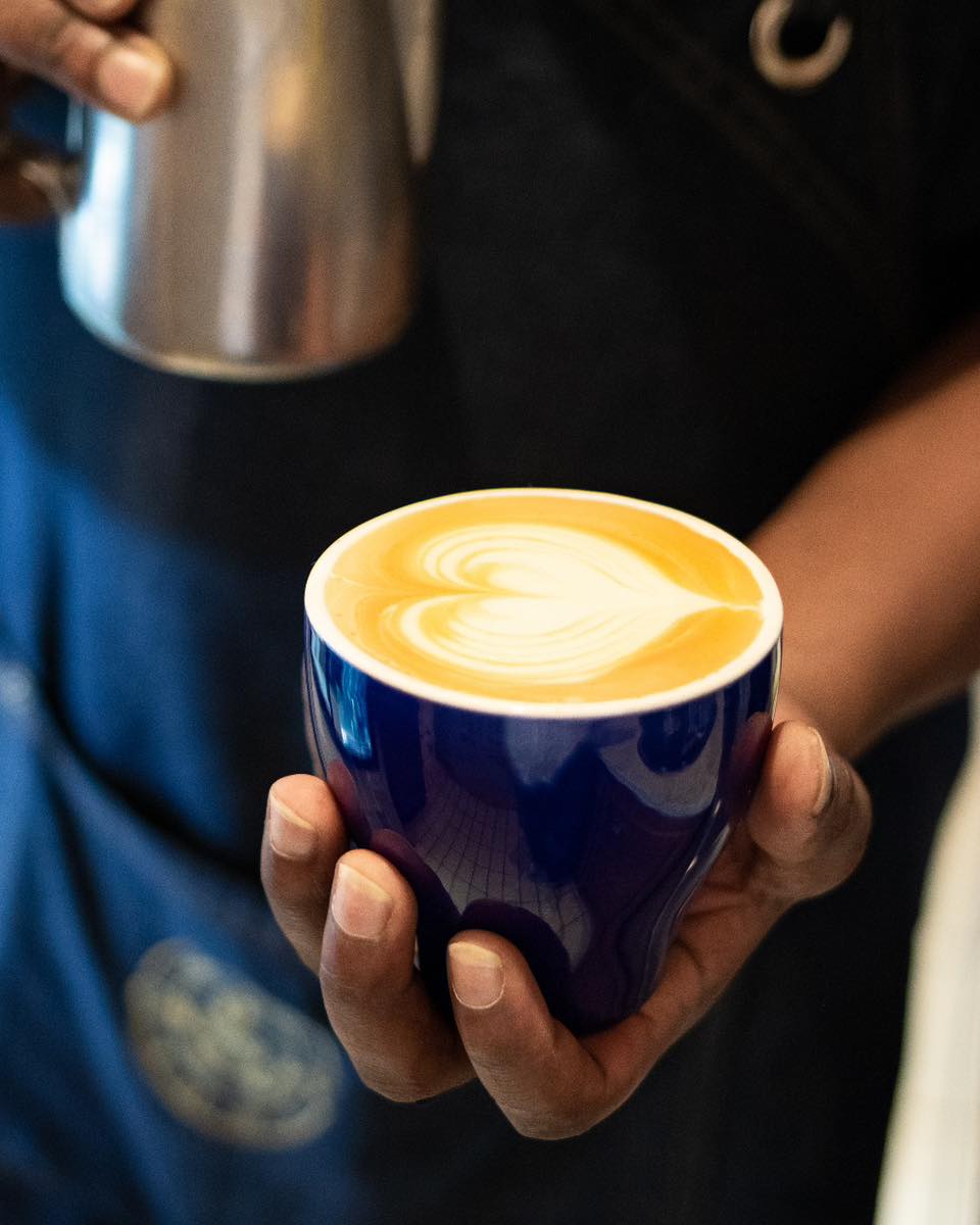 Cappuccino in a navy ceramic cup with latte-art heart